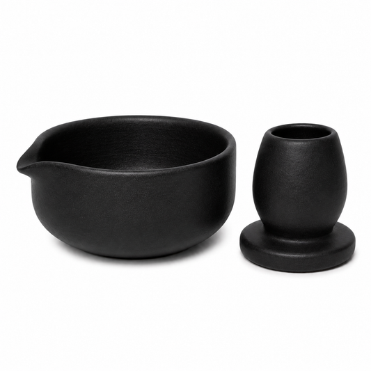 A matte black ceramic matcha set featuring a bowl with a pouring spout and a small matching cup on a white background.