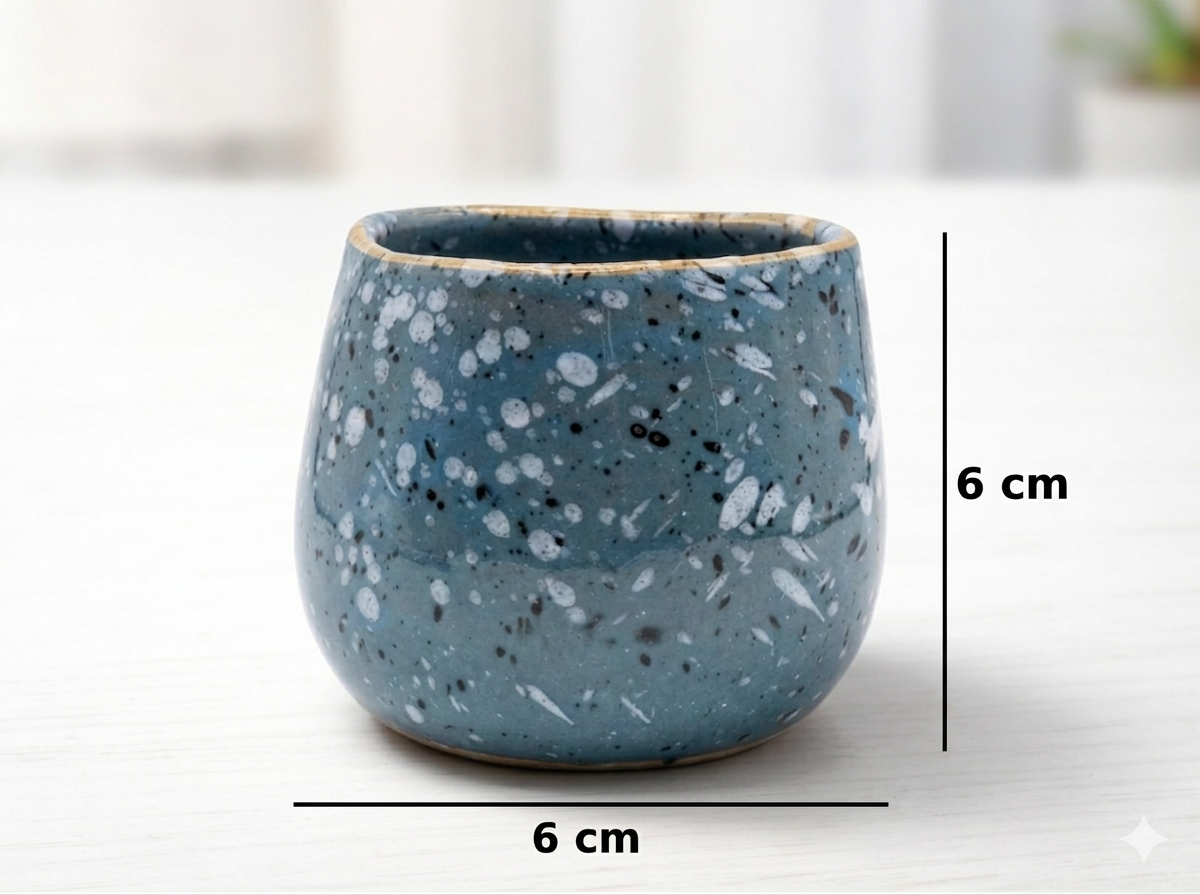 Blue speckled ceramic cup with measurements on a white background