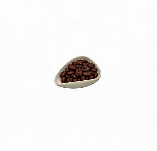 Triangular ceramic bowl filled with coffee beans on a white background