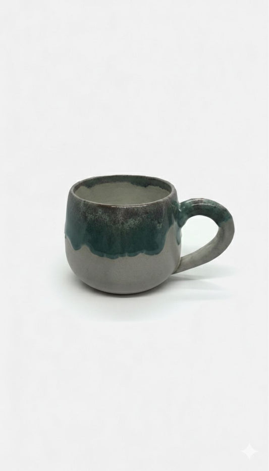 Ceramic mug with a greenish-blue glaze on a white background