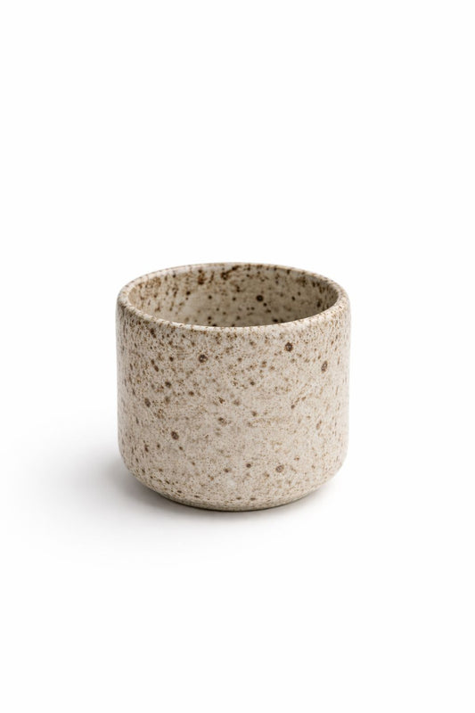 Speckled ceramic cup on a white background