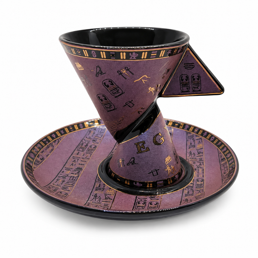 A purple and black ceramic coffee cone cup with a matching saucer, decorated with gold hieroglyphic symbols and letters, set against a plain white background.