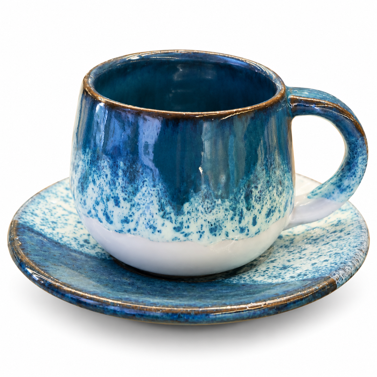 A handmade ceramic coffee cup and saucer set in shades of blue and white with a rustic gold-brown rim, shown on a clean white background.
