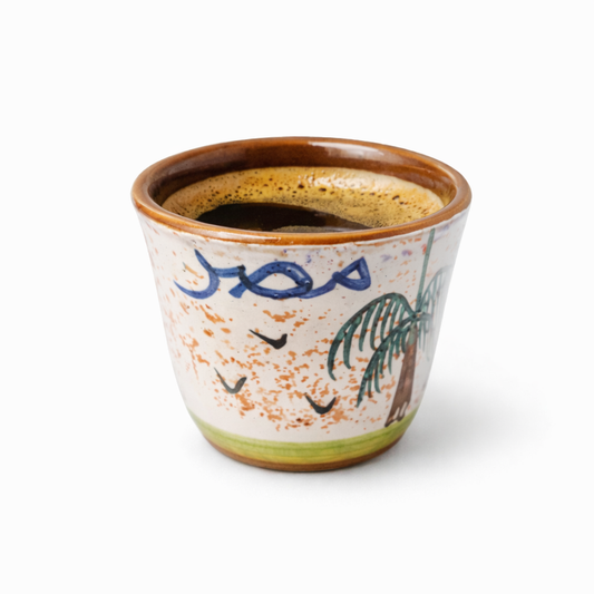 Ceramic cup with brown rim and colorful design on a white background