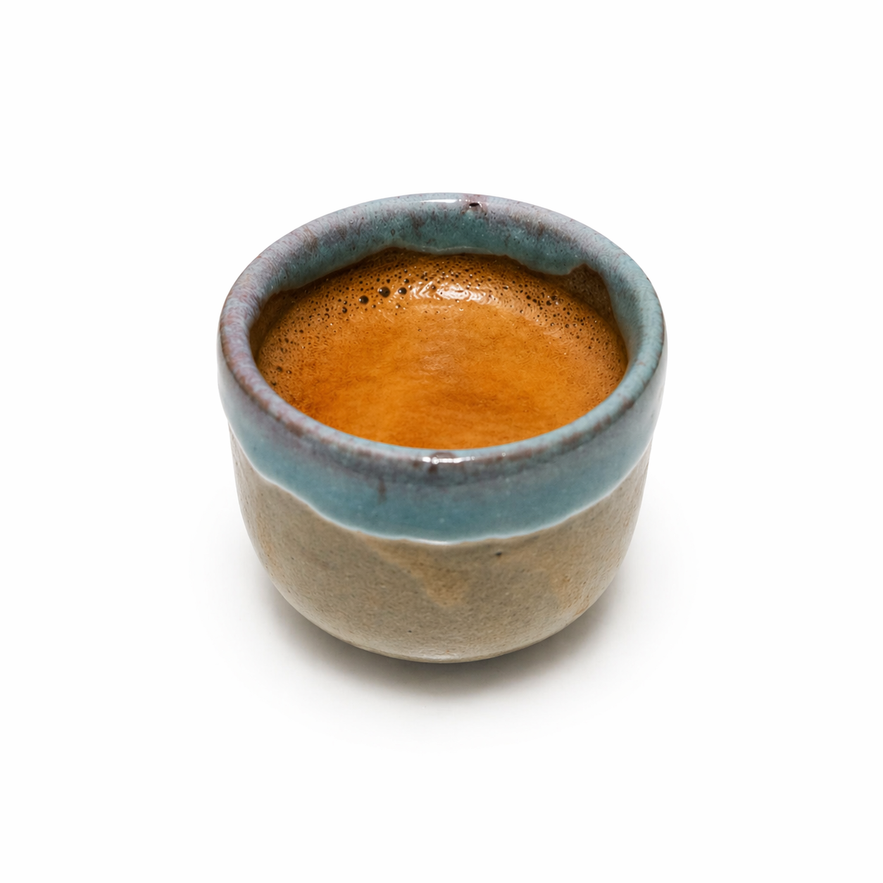 Ceramic cup with a blue rim and brown interior filled with a dark liquid on a white background