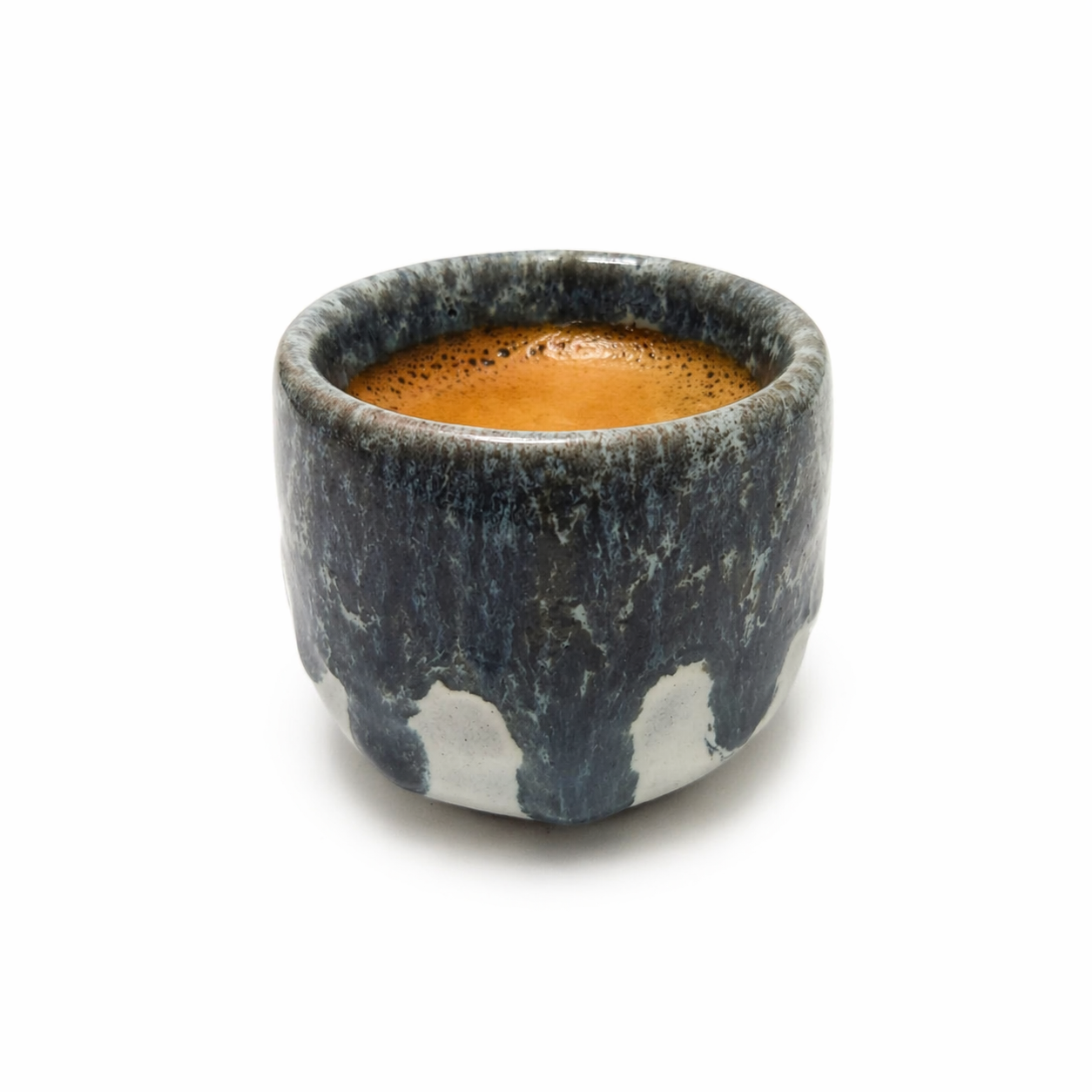 Ceramic cup with a dark marbled pattern filled with a brown liquid on a white background