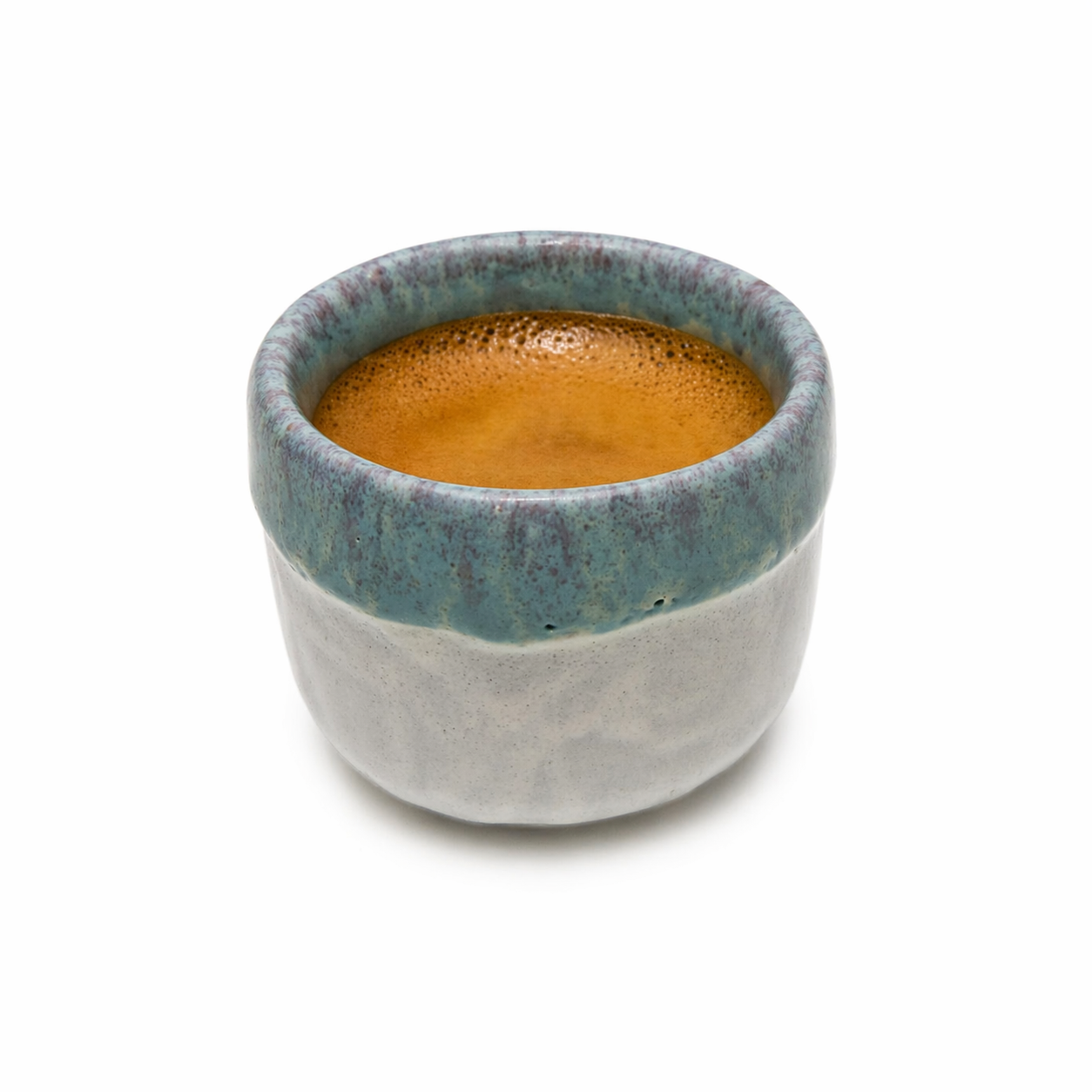 Ceramic cup with a textured blue rim and gray base containing a brown liquid on a white background