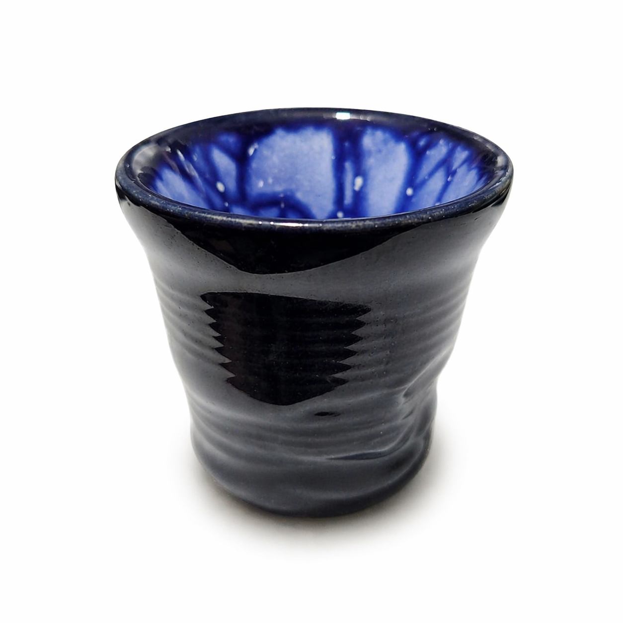 Ceramic cup with blue interior and black exterior on a white background