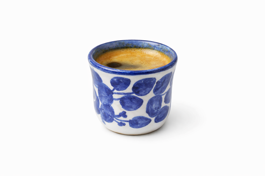 Ceramic cup with blue floral patterns filled with a beverage on a white background