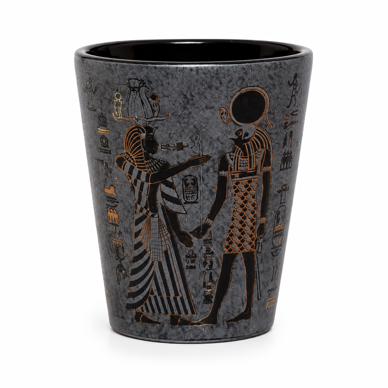 A dark gray textured ceramic shot glass featuring an Egyptian design with black figures and gold hieroglyphs, set against a plain white background.