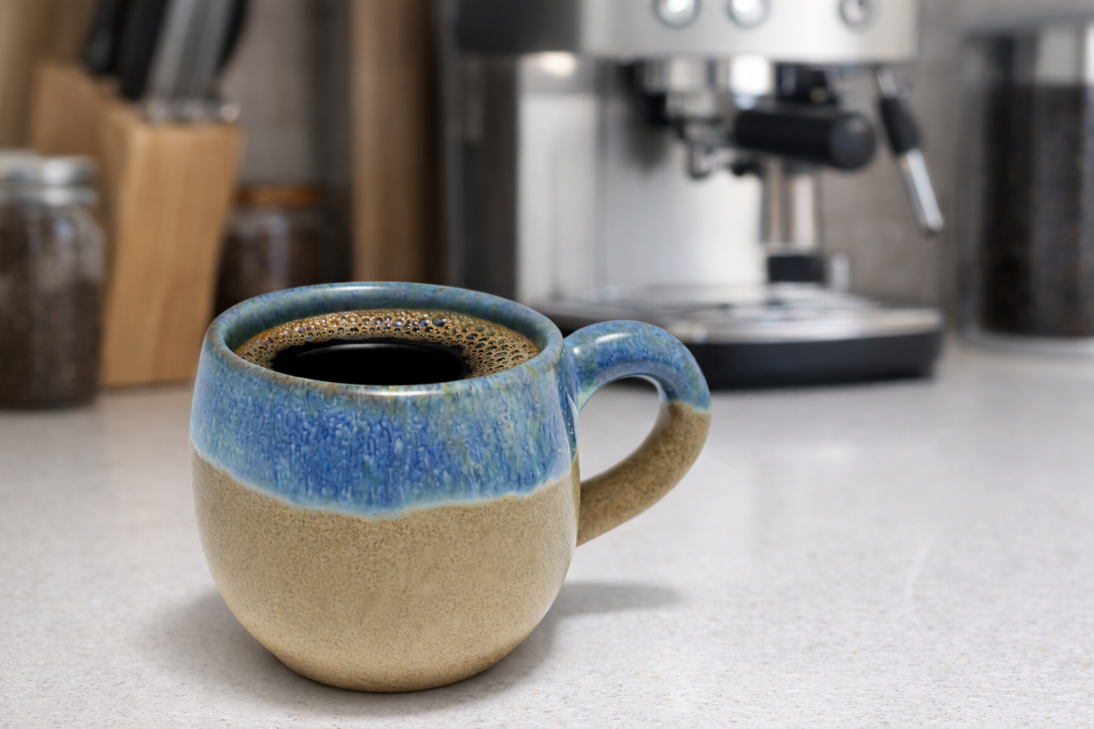 Ceramic mug with blue rim and brown body on a kitchen counter with coffee machine in the background