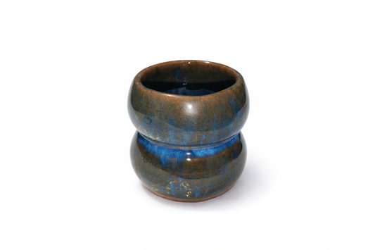 Ceramic cup with blue glaze on a white background