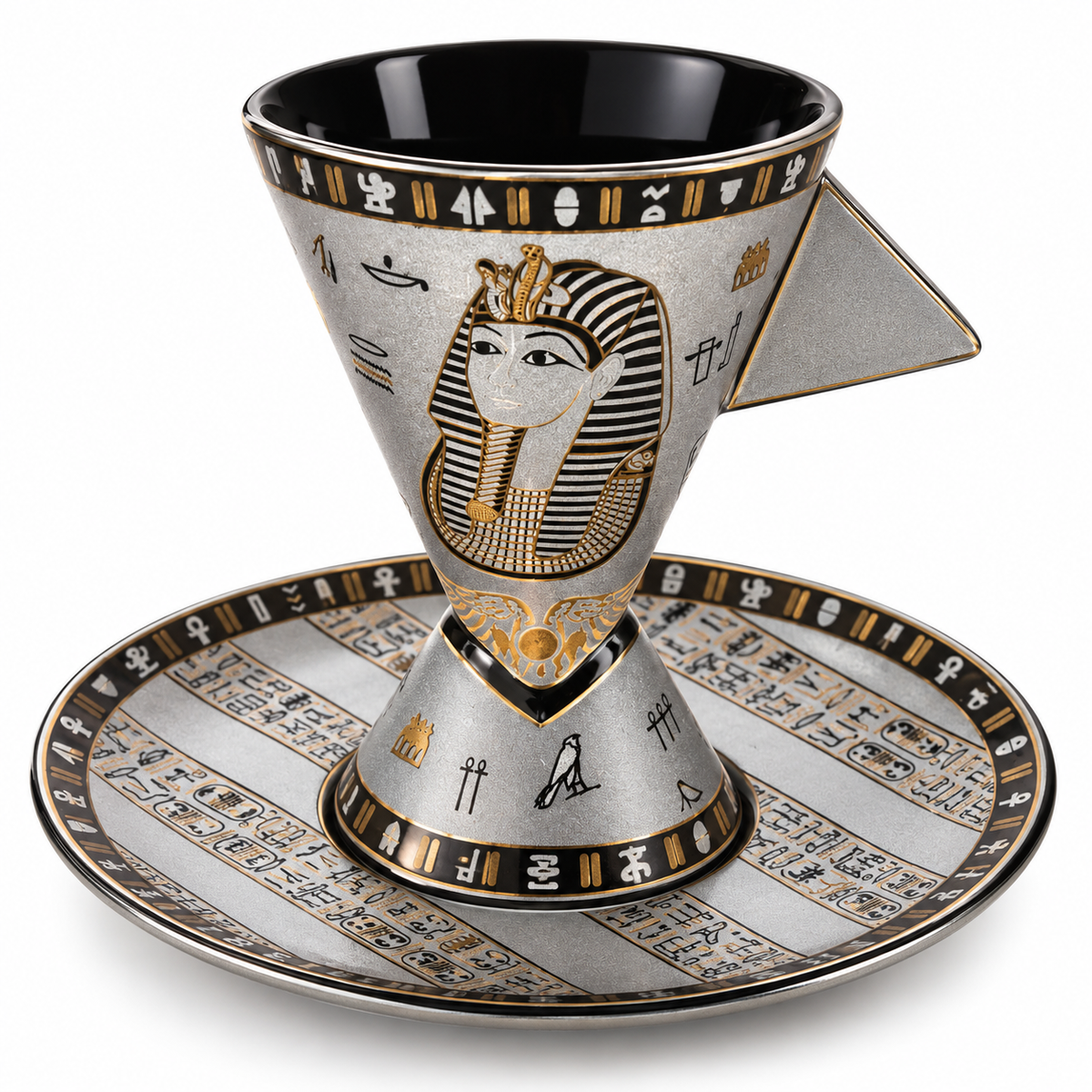 An Egyptian-themed ceramic coffee cup and saucer set. The cup features a gold and black pharaoh design on a silver-toned base, with a matching saucer decorated with gold and black hieroglyphs.
