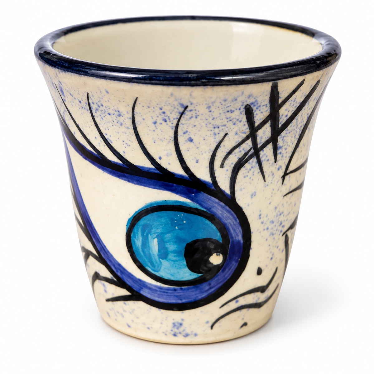 A handmade ceramic eye-shaped cup with a blue and black painted design on a speckled cream background, set against a plain white studio background.