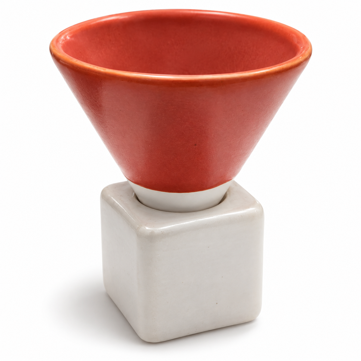 A ceramic funnel-shaped cup in a warm terracotta red glaze, mounted on a matte off-white square pedestal base, photographed on a clean white background.