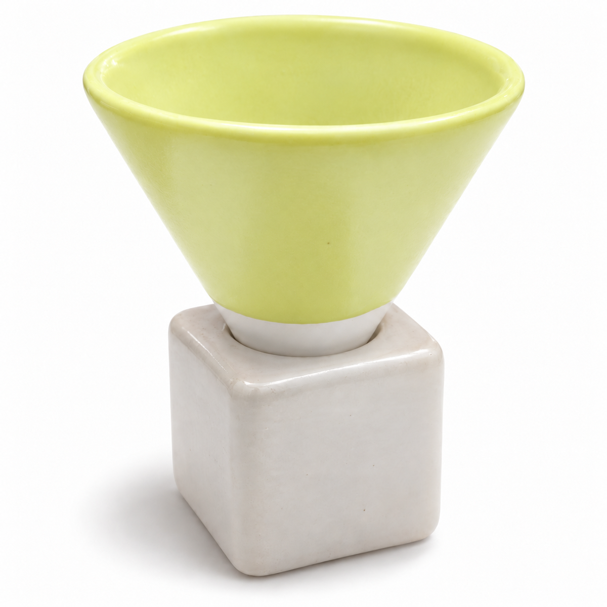A ceramic funnel-shaped cup in pale yellow-green sits on a matte off-white square pedestal base against a clean white background.