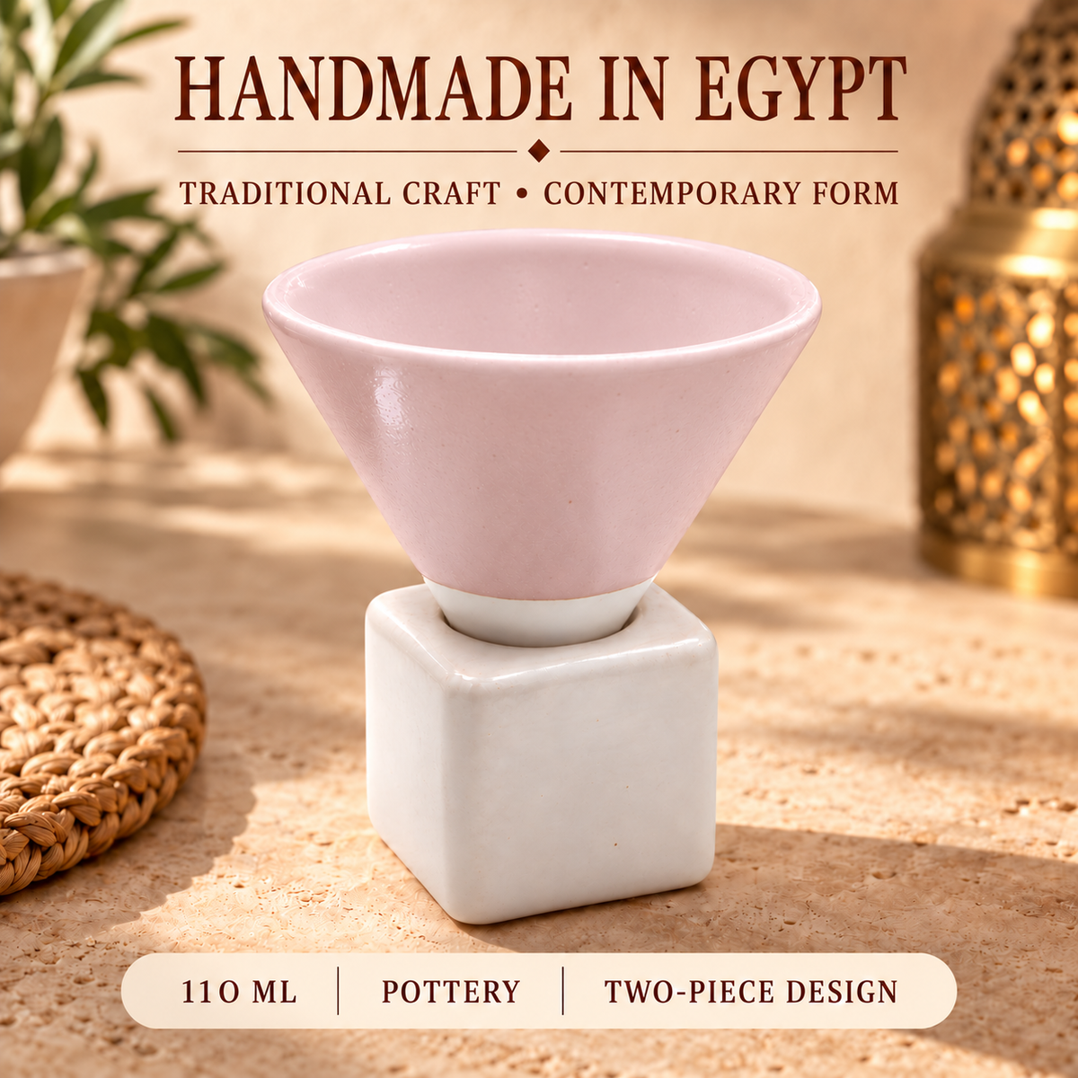 A two-piece ceramic cup set featuring a light pink conical bowl resting on a white square base, displayed on a sandy surface with decorative props and text overlays.