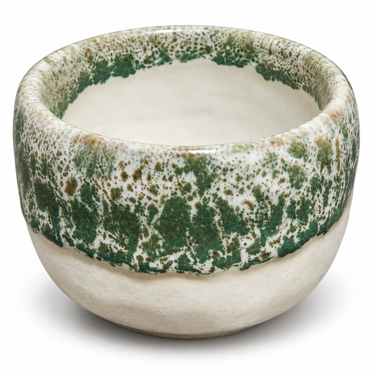 A handmade ceramic bowl with a textured, speckled green and beige glaze on the upper half and a smooth, matte cream-colored lower half, shown on a white background.
