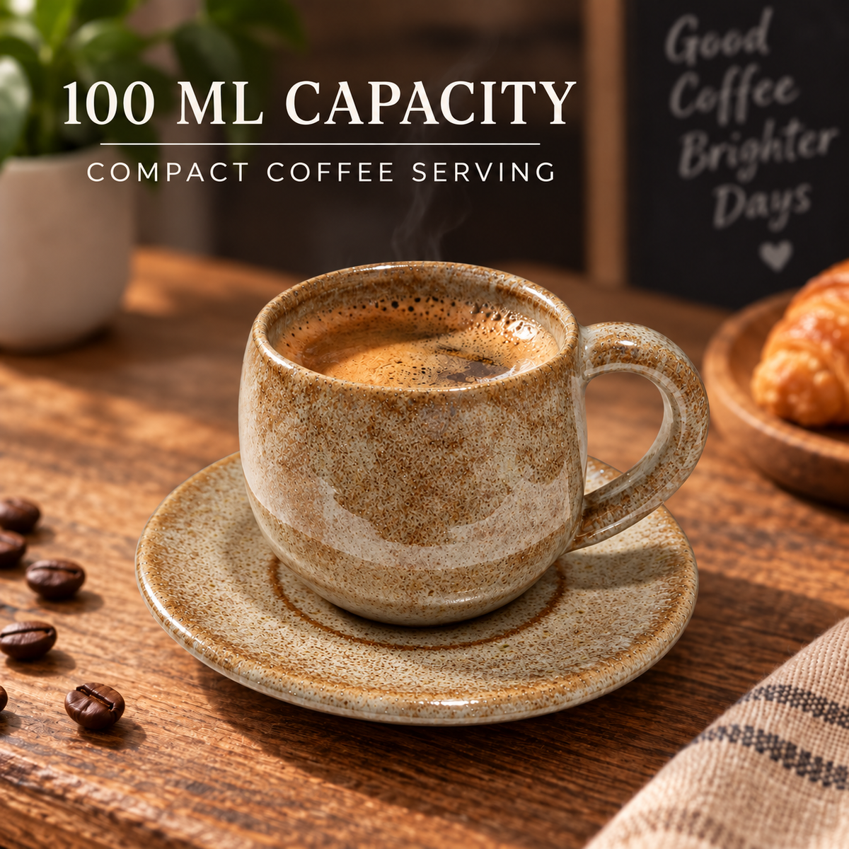 A ceramic coffee cup and saucer set on a wooden table, filled with espresso and shown with text reading '100 ML CAPACITY' and 'COMPACT COFFEE SERVING.' Coffee beans, a plant, and a croissant are visible in the background.