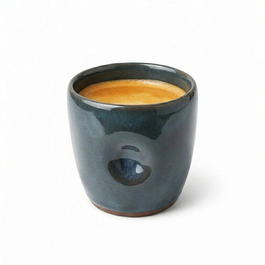 Dark blue ceramic cup with a handle filled with a frothy beverage on a white background