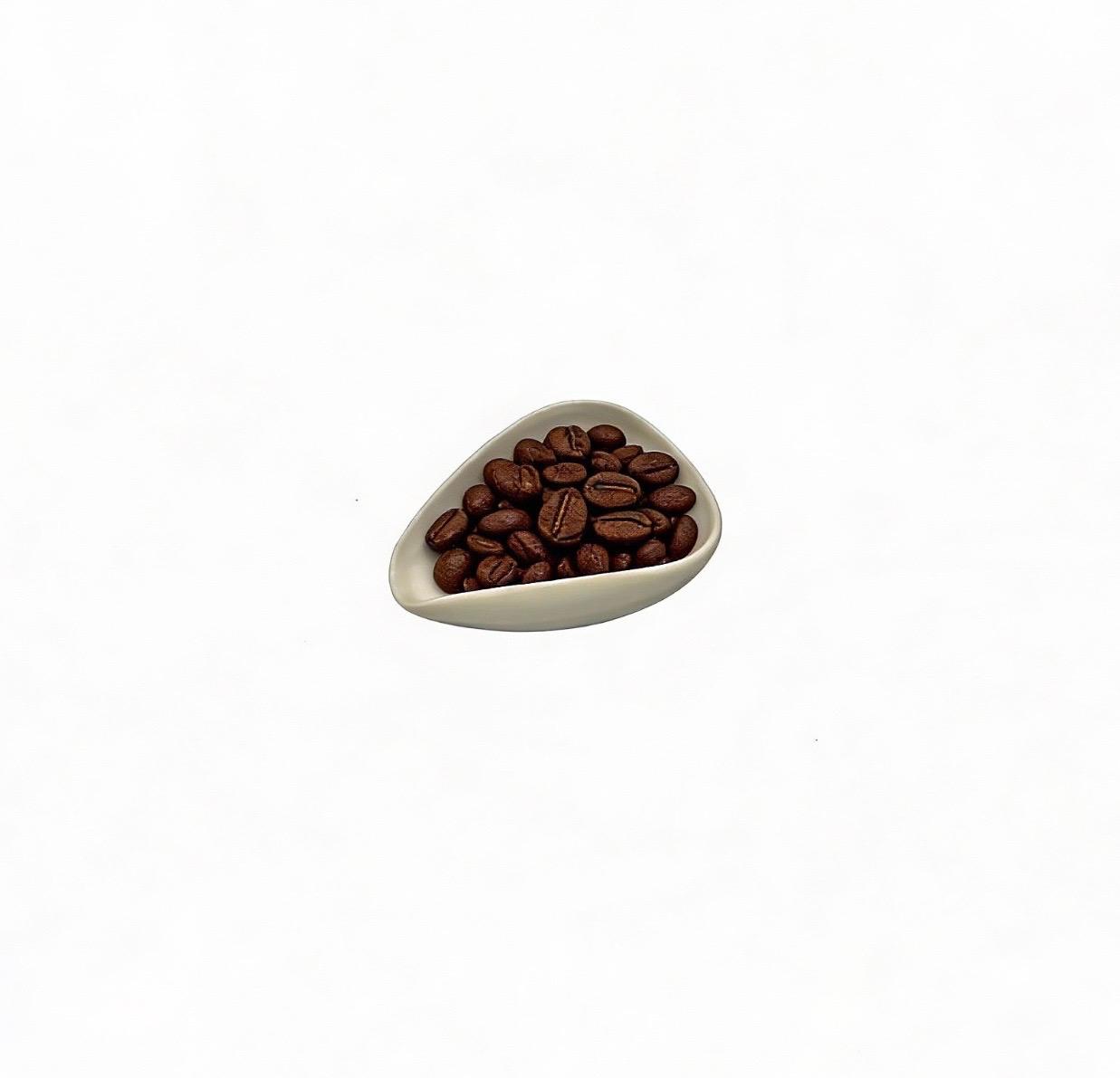 Triangular ceramic bowl filled with coffee beans on a white background