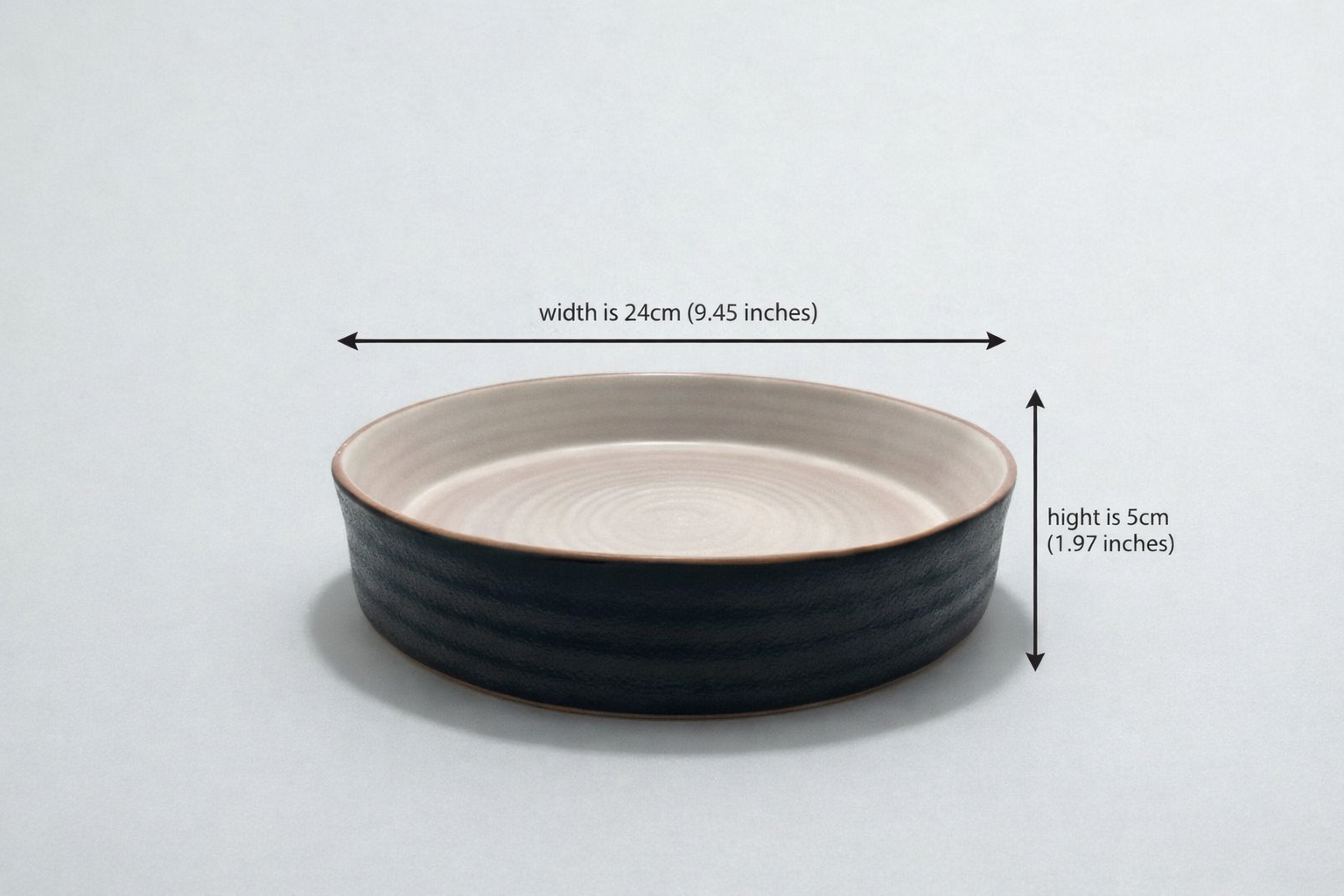 Black ceramic bowl with measurements on a light gray background