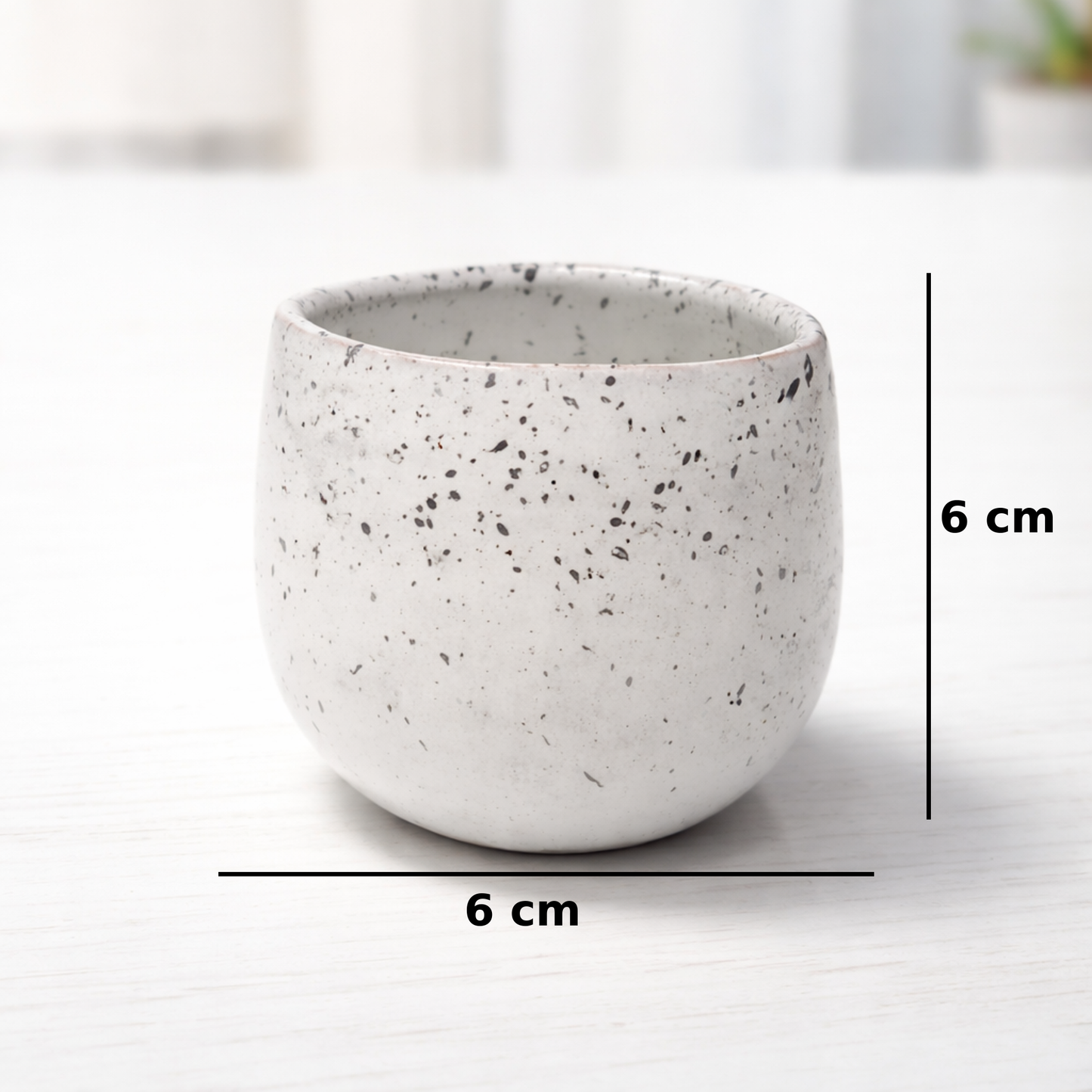 White ceramic cup with speckled texture on a white background, showing measurements.