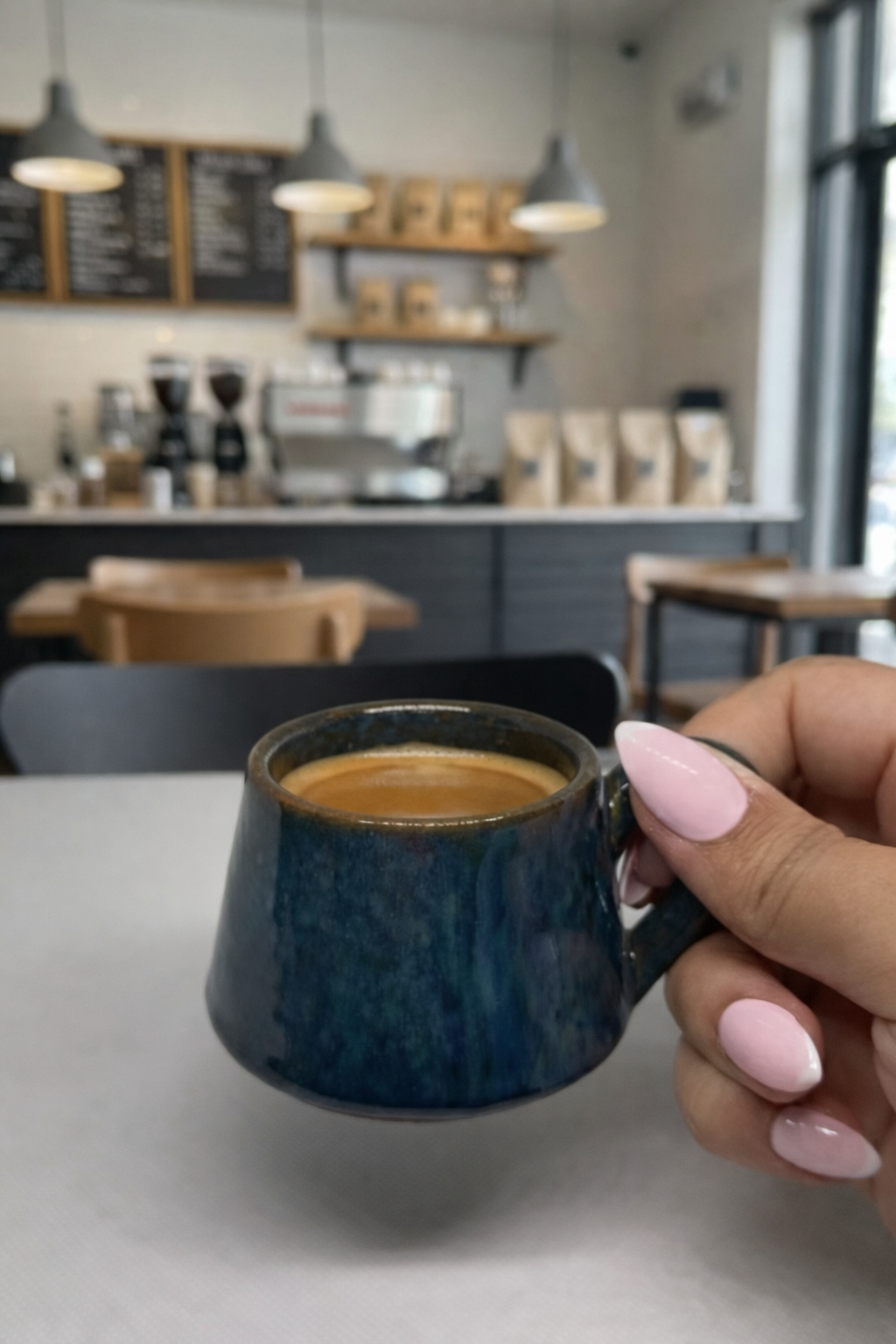 Person holding a blue mug with coffee in a cafe setting