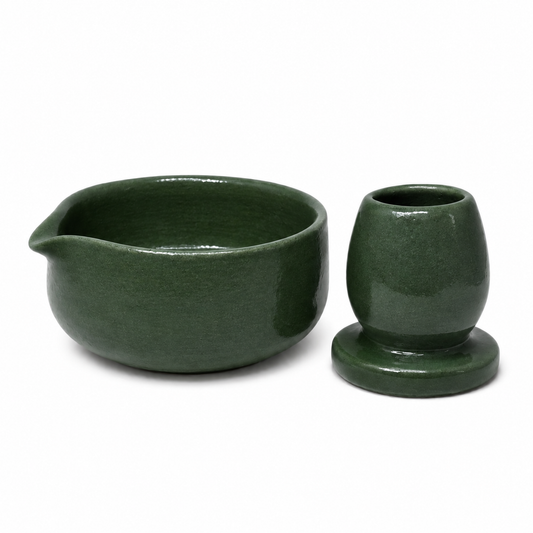 A dark green glazed ceramic tea set with a small pitcher and a matching cup or holder on a white background.