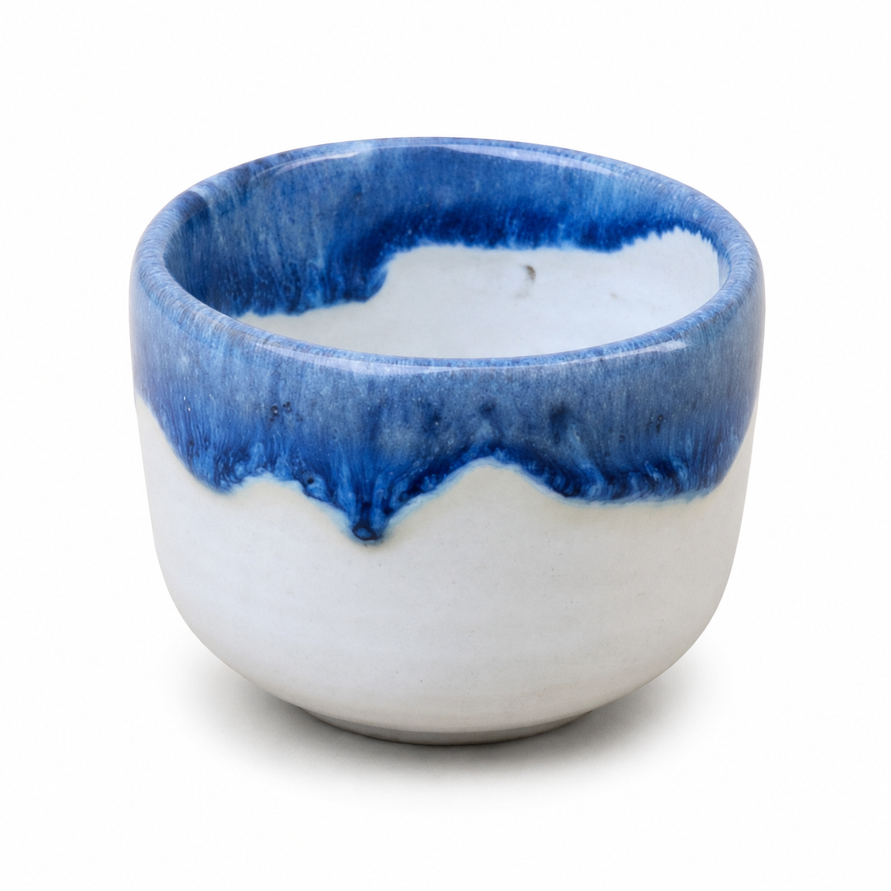 A small ceramic cup or candle holder with a glossy white body and a vibrant blue dripping glaze around the rim, shown on a clean white background.