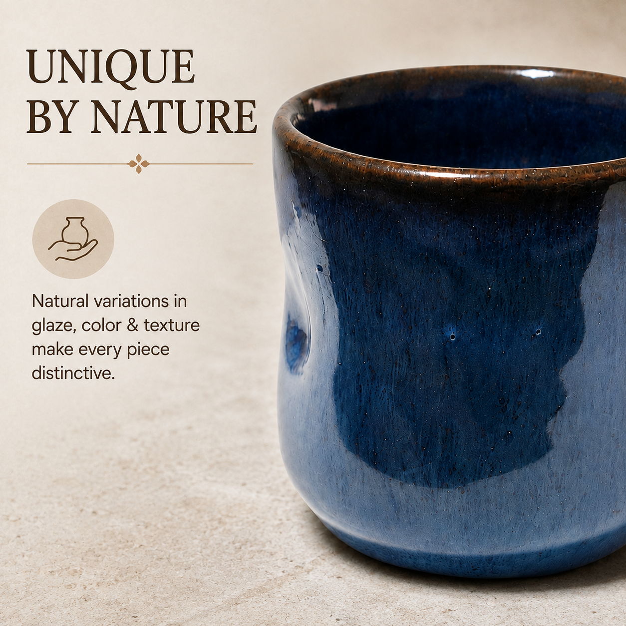 A close-up of a ceramic cup with a deep blue to navy glossy glaze and a dark brown rim, shown on a textured beige surface with promotional text reading 'UNIQUE BY NATURE' and a small icon about natural variations in glaze color and texture.