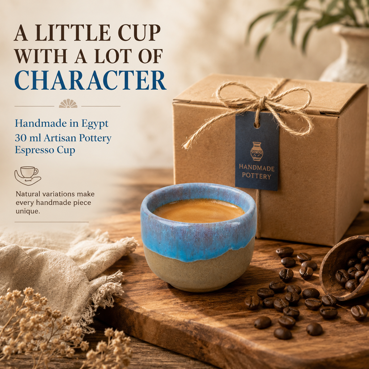 A handmade ceramic espresso cup with a blue glazed rim and beige base, filled with coffee, styled on a wooden board with coffee beans, a kraft gift box tied with twine, and text on the left reading 'A LITTLE CUP WITH A LOT OF CHARACTER'.