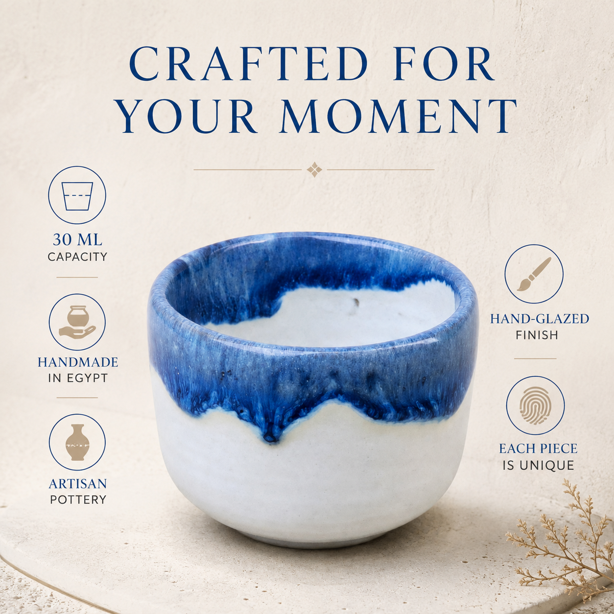 A handcrafted ceramic cup with a blue and white glazed finish, presented on a textured beige background with promotional text and icons highlighting its 30 ml capacity, handmade in Egypt, artisan pottery, and hand-glazed finish.