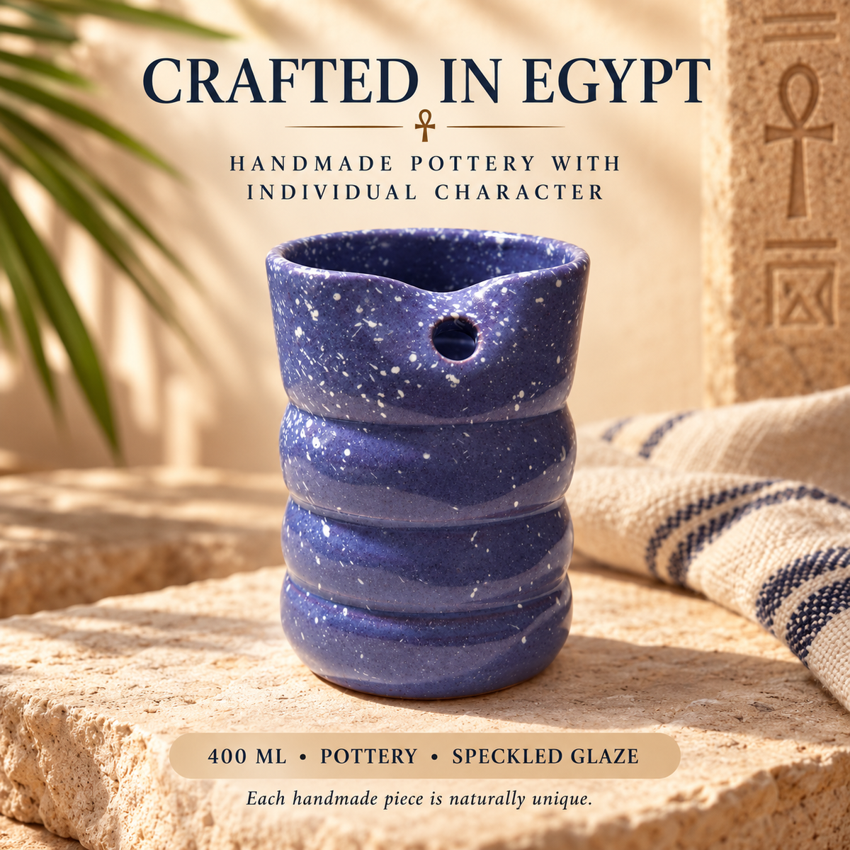 A speckled cobalt blue ceramic pitcher with a small pouring hole, displayed on a stone surface with Egyptian-themed props and text overlays.