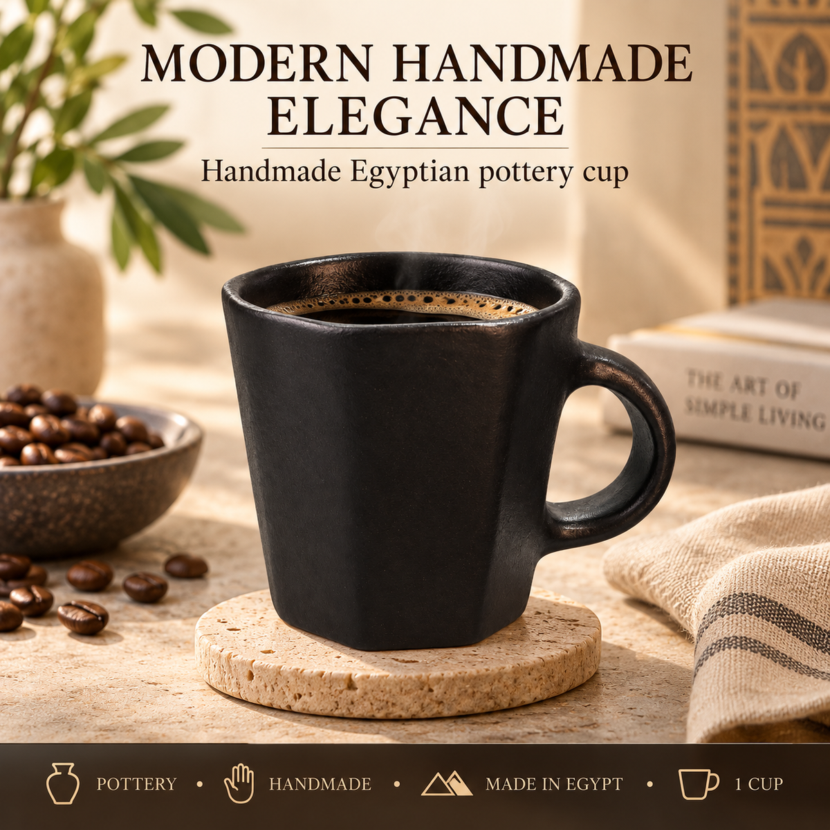 A matte black handmade Egyptian pottery coffee cup with a hexagonal shape and a loop handle, sitting on a cork coaster on a rustic table with coffee beans, a book, and a striped cloth.