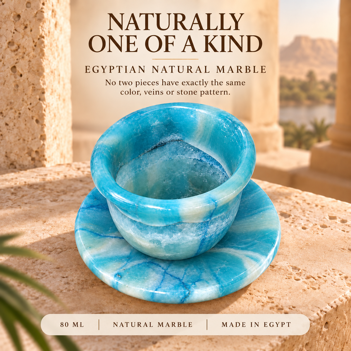 A blue and white marbled Egyptian natural marble cup with a matching saucer, displayed on a stone surface with a warm desert background. Text overlays describe the product as 'Egyptian Natural Marble' and 'Naturally One of a Kind'.