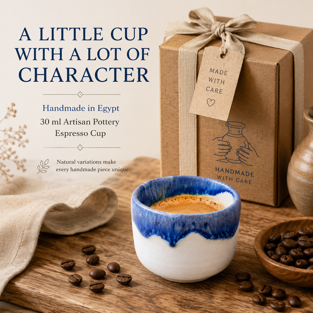 A handmade ceramic espresso cup with a blue and white glazed finish, filled with espresso, displayed on a wooden table with coffee beans. Behind it is a brown kraft gift box tied with a beige ribbon and tag that reads 'MADE WITH CARE'.