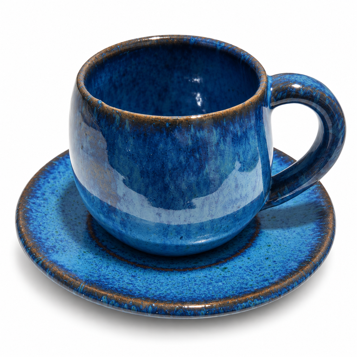 A blue glazed ceramic espresso cup with a matching saucer, featuring a rich cobalt blue finish with a rustic brown rim, set against a plain white background.