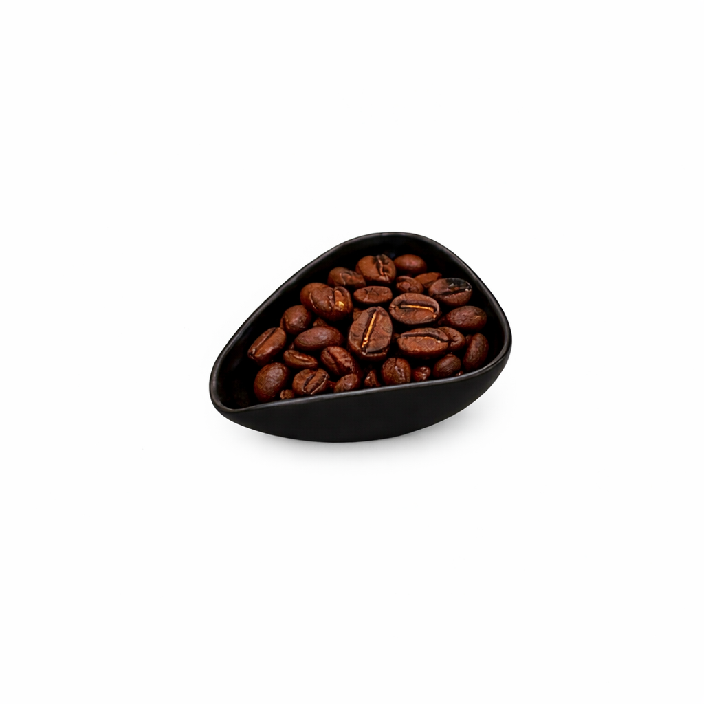 Black triangular ceramic bowl filled with coffee beans on a white background
